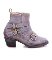 A side view of the Bady short leather boot from Oak Tree Farms with two brass buckle straps, a low heel, and a slightly worn appearance.