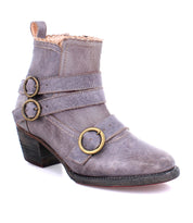 A gray short leather boot with two decorative brass buckles and a short heel, featuring a textured leather finish, the Bady by Oak Tree Farms.