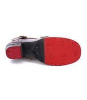 Image of the underside of a ladies leather boot, revealing a red sole with a few circular logos and black heel. The handmade Oak Tree Farms Bady appears to have stitching around the edge of the sole.