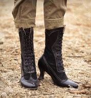 A woman's Oak Tree Farms Abigale boot-clad legs are standing on a pile of dirt, showcasing charming details.