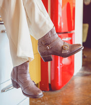 A person's legs, clad in Oak Tree Farms' Bady boots, hanging off of a refrigerator.