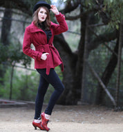A woman in a red coat with a neutral look, posing in a wooded area wearing Oak Tree Farms leather shoes with lace-up front, named Janet.