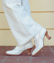A woman wearing white pants and white shoes, dancing gracefully in hand dyed Oak Tree Farms' Jasmine leather boots.