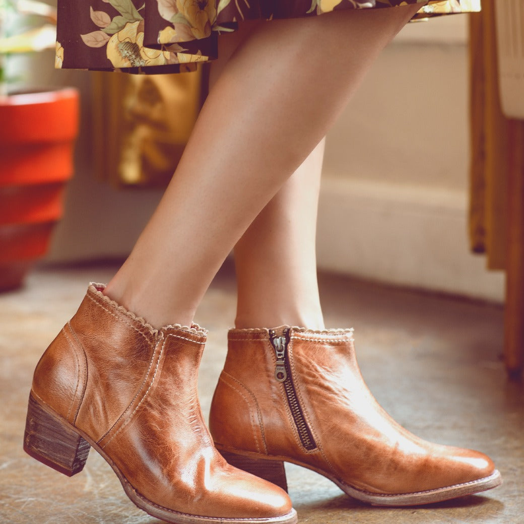 A woman in a floral dress wearing Oak Tree Farms tan leather ankle boots for comfort and to enhance her wardrobe.
