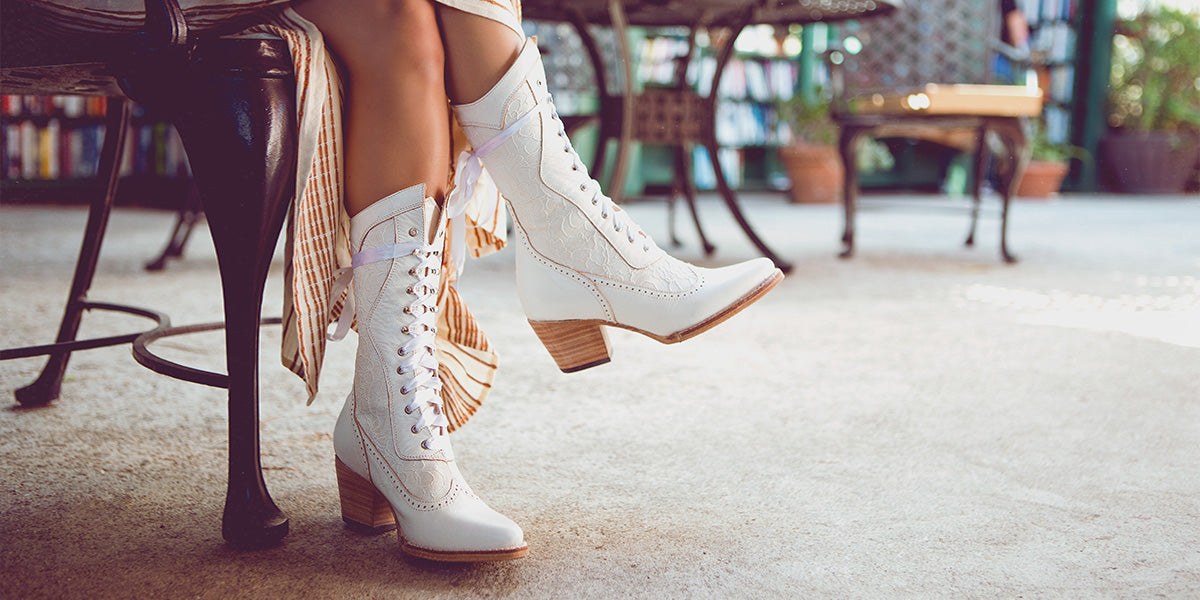 A woman is sitting on a bench wearing white boots.