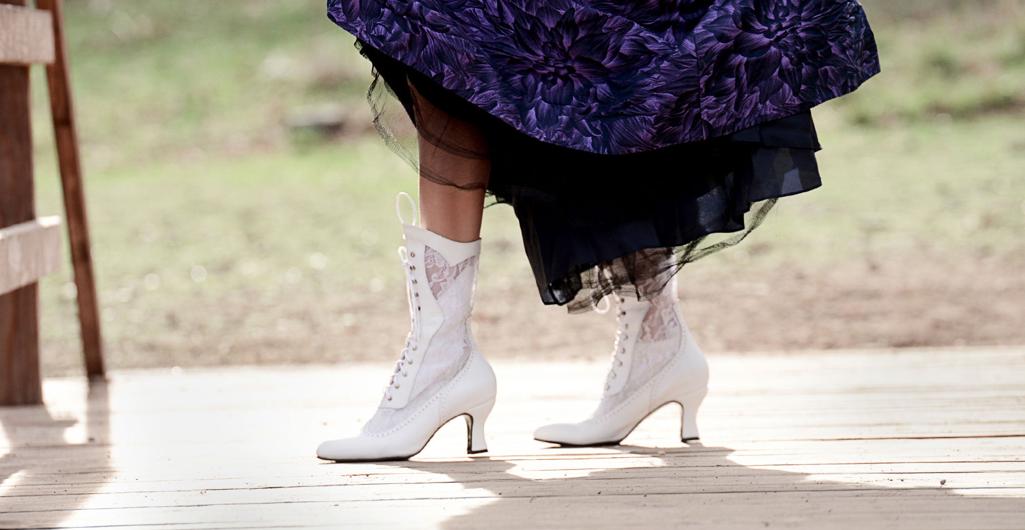 A woman wearing a purple dress and white boots.