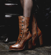 A woman donning a pair of Oak Tree Farms Amelia boots equipped with fishnet stockings, showcasing the exquisite craftsmanship of full grain leather and Goodyear leather welt.