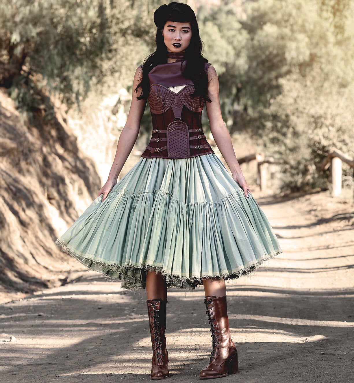 A woman wearing the "Ariana" lace skirt and "Oak Tree Farms" leather boots on a dirt road.