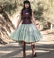 A woman wearing the "Ariana" lace skirt and "Oak Tree Farms" leather boots on a dirt road.