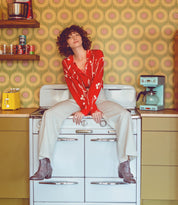 A woman, adorned in Oak Tree Farms Bady boots, sits upon a stove in a kitchen.