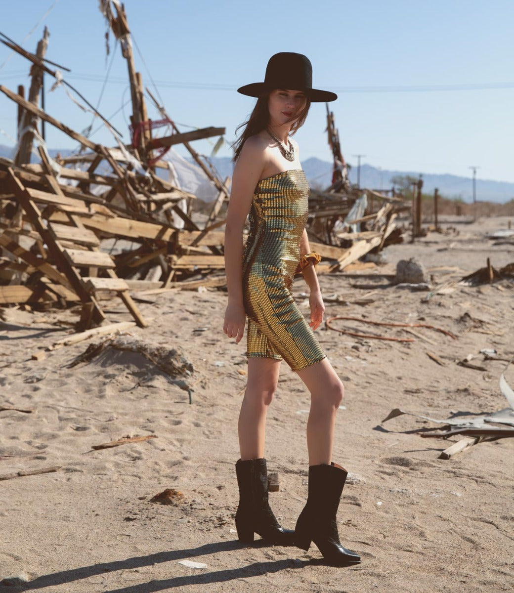 A woman in a Basanti dress, wearing Oak Tree Farms leather boots with pointed toe, standing in a deserted area.