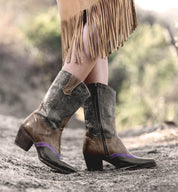 Oak Tree Farms Basanti, a woman wearing hand tooled leather cowboy boots and a fringe skirt.