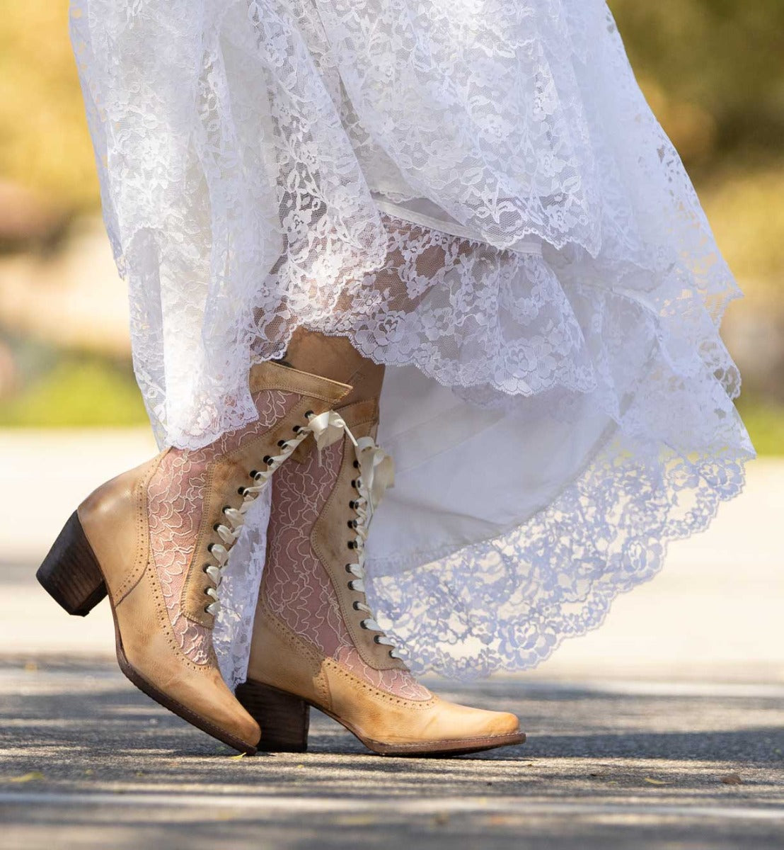 A bride in a white dress wearing seductive Oak Tree Farms Biddy black leather boots.