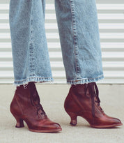 A woman wearing Oak Tree Farms' Eleanor hand-dyed jeans paired with a stylish Victorian-style brown boots, showcasing uncompromising quality.
