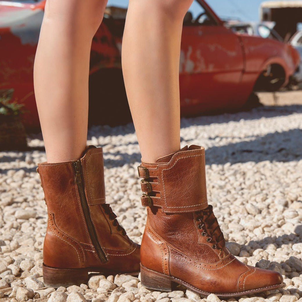 A woman's legs standing on gravel in a pair of Oak Tree Farms handcrafted brown riding boots named Faye.