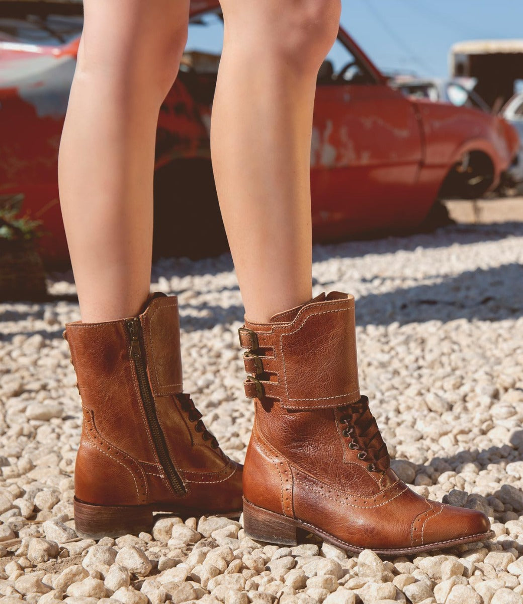A woman's legs standing on gravel in a pair of Oak Tree Farms handcrafted brown riding boots named Faye.