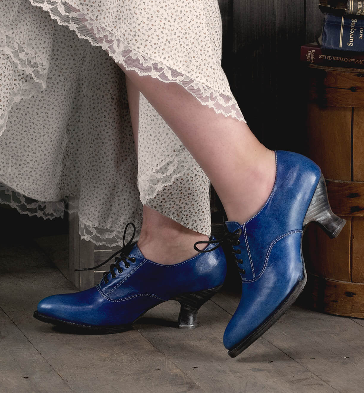 A woman's feet in Oak Tree Farms' Janet lace-up leather shoes on a wooden floor with a neutral look.