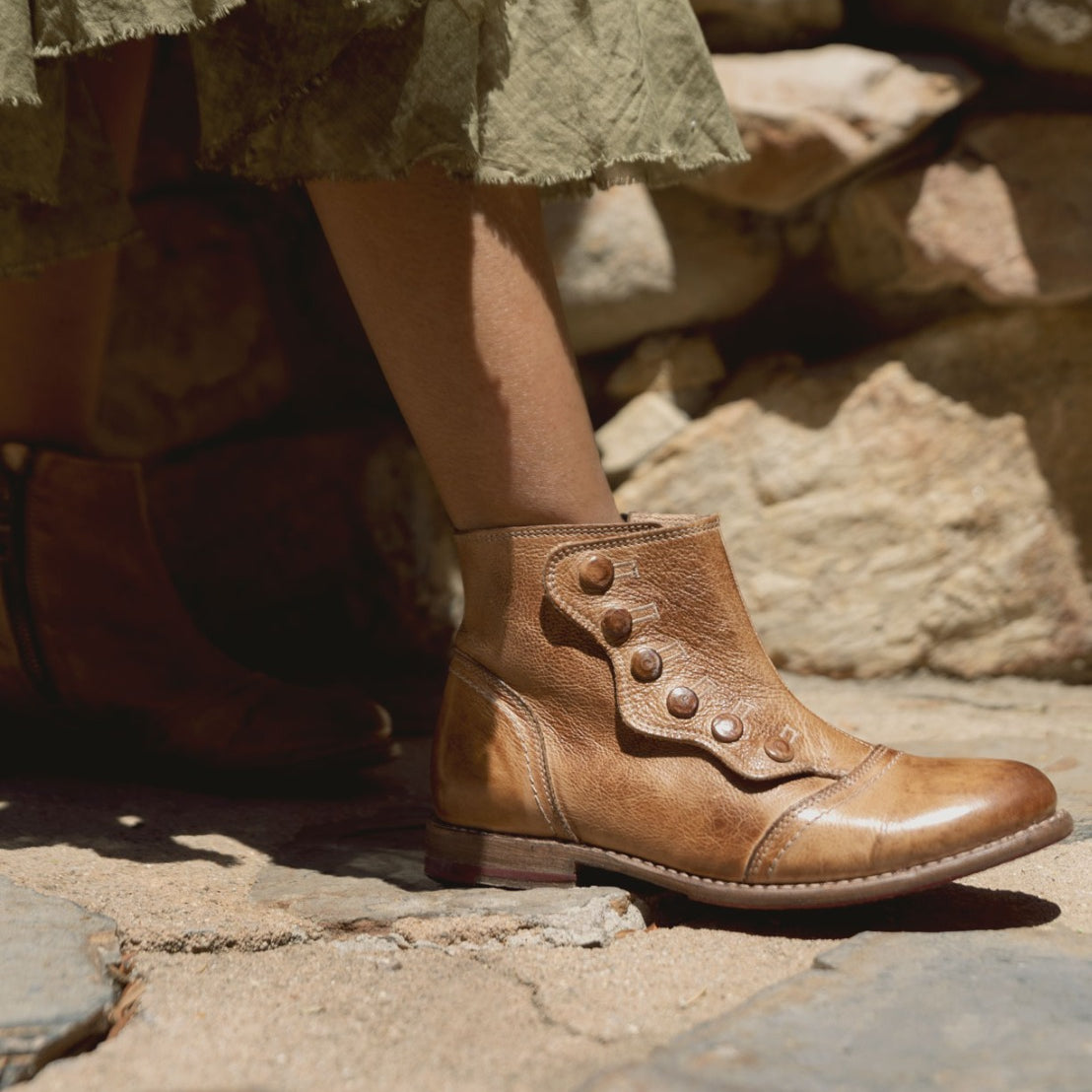 A woman's feet in a pair of Oak Tree Farms Josephine tan leather booties featuring YKK zippers.