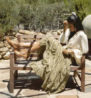 A woman wearing a green skirt and Oak Tree Farms Josephine booties, sitting on a wooden bench.