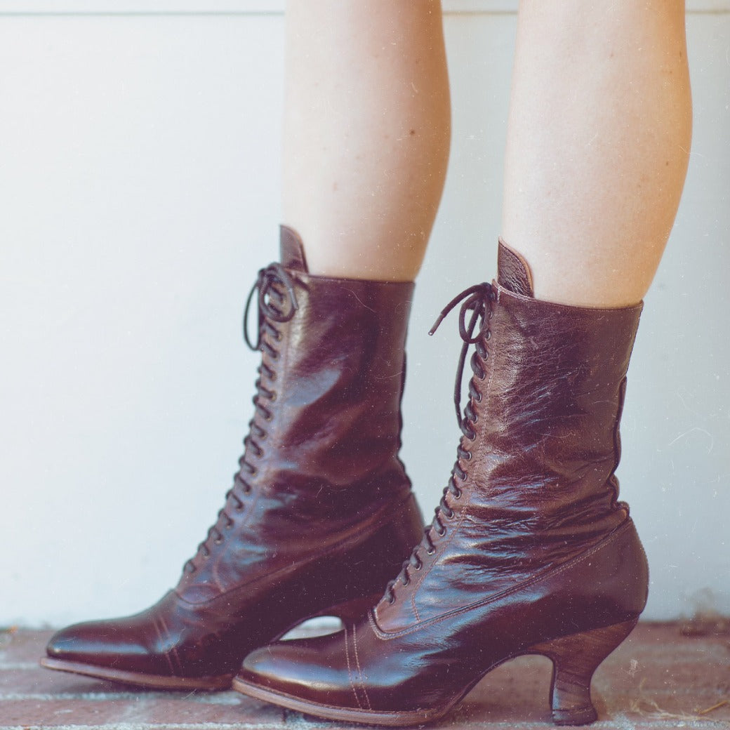 Oak Tree Farms' Mirabelle legs adorned with grommet laces on her brown leather boots.