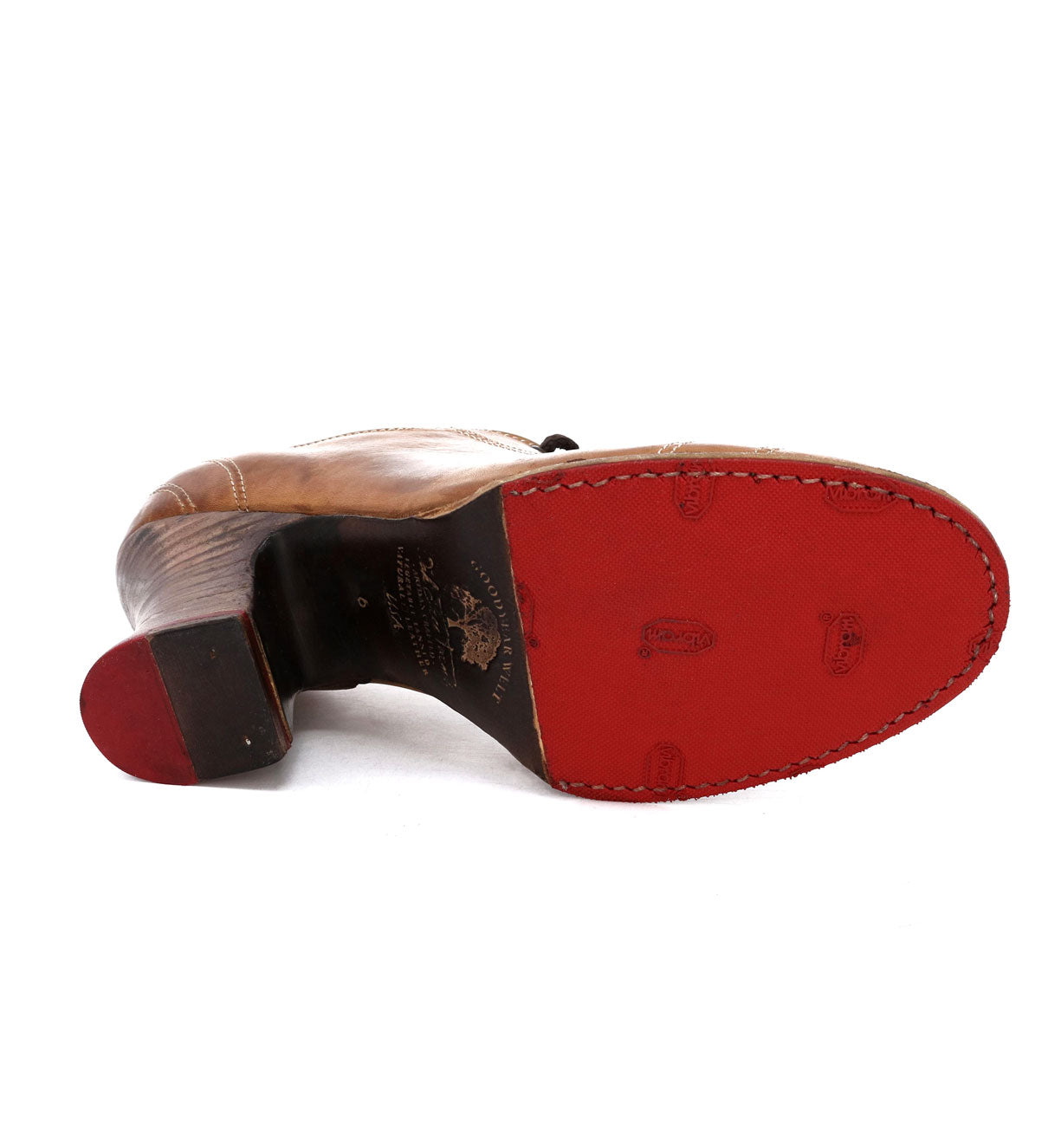 A pair of Oak Tree Farms Nanny red shoes with vibrant soles mesmerizingly enchant the viewer on a crisp white background.