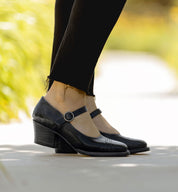 A woman's feet in black Mary Jane shoes, the classic leather shoe with a stylish Oak Tree Farms Twigley twist.